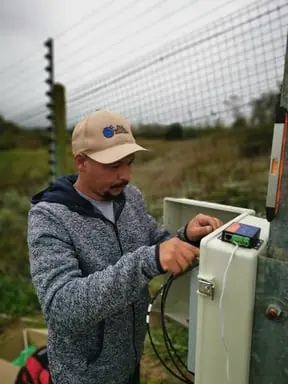 Technician wiring an electric fence energiser