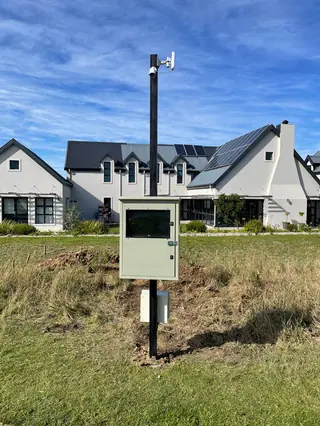 Camera and beam pole with control box outside a house