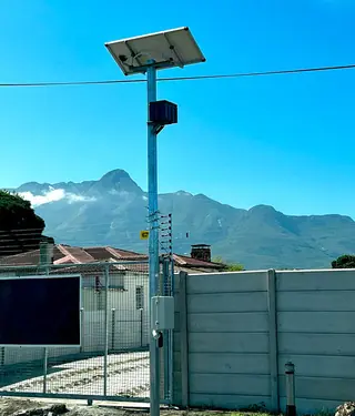 Solar-powered electric fence energiser on a pole with mountains behind