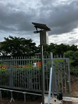 Solar panel powering a fence energiser beside a palisade fence