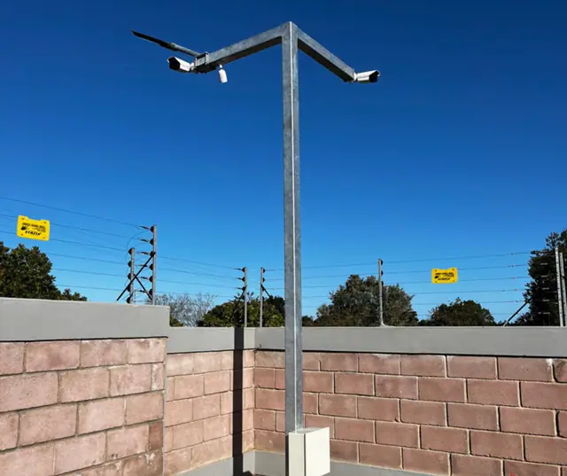 Two CCTV cameras on a galvanised pole against a blue sky