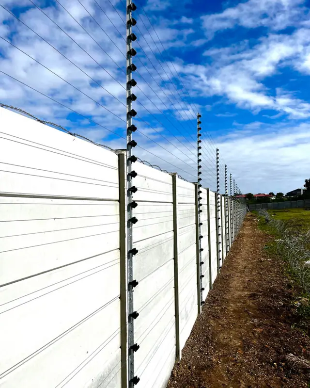 Electric fencing along a white boundary wall