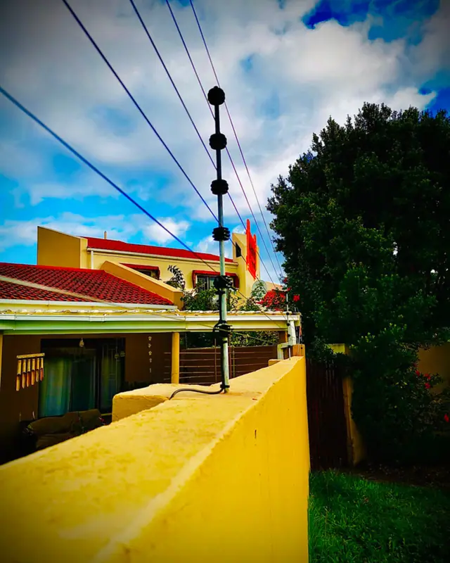Electric fencing on a yellow boundary wall